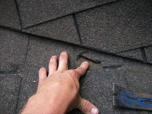 Upclose photo of roofing with a roofer's hand